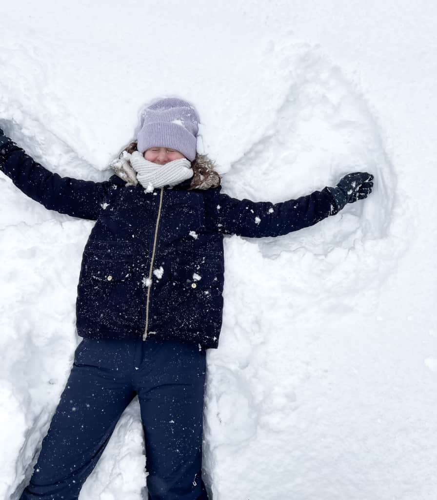 Mädchen im Schnee macht Schneeengel, nachhaltige Familienaktivitäten